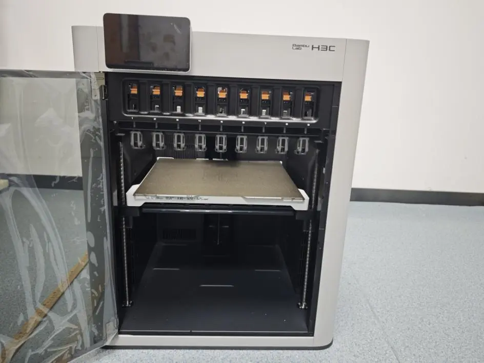 Bambu Lab H3C with its door open, showing nine numbered docks across the top of the build chamber