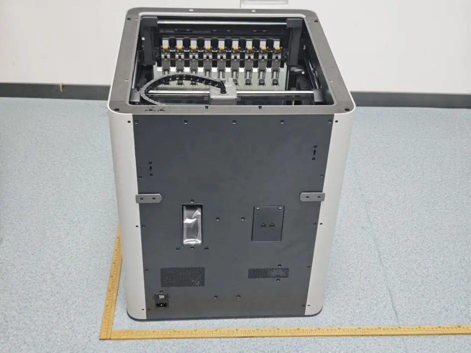 Rear of the Bambu Lab H3C with the top open, showing nine parked hotends in a row along the front of the chamber