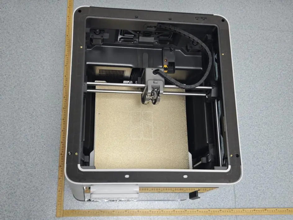 Top-down view into the Bambu Lab H3C showing a single toolhead on the gantry above a textured build plate